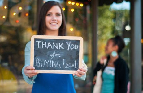 Woman standing, holding up a thank you sign.